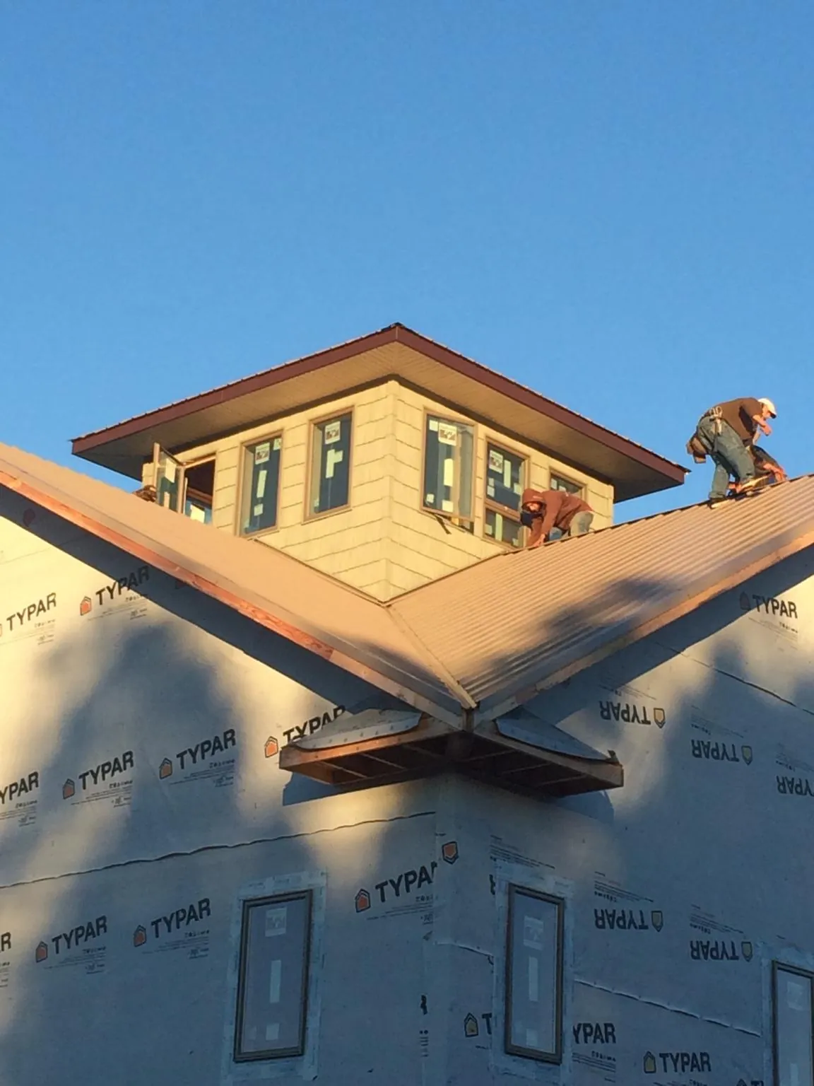 Roofers working around a rooftop cupola on a new metal roof at sunset — Roof Waterproofing in Derby by Roofing Brothers